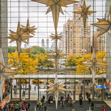 Holiday decorations in the Shops at Columbus Circle with a view of the fountain and trees through the glass façade.